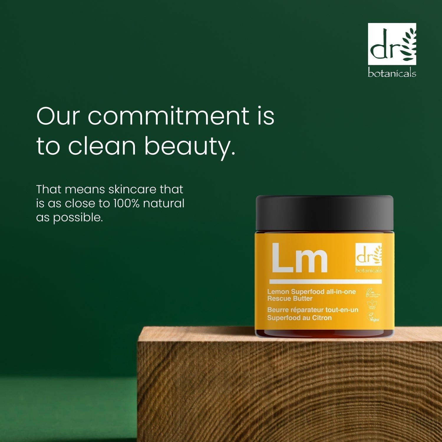Gelber Tiegel mit "Lm" und "dr botanicals" auf Holzblock. Text: Lemon Superfood all-in-one Rescue Butter. Aufschrift: Clean Beauty.