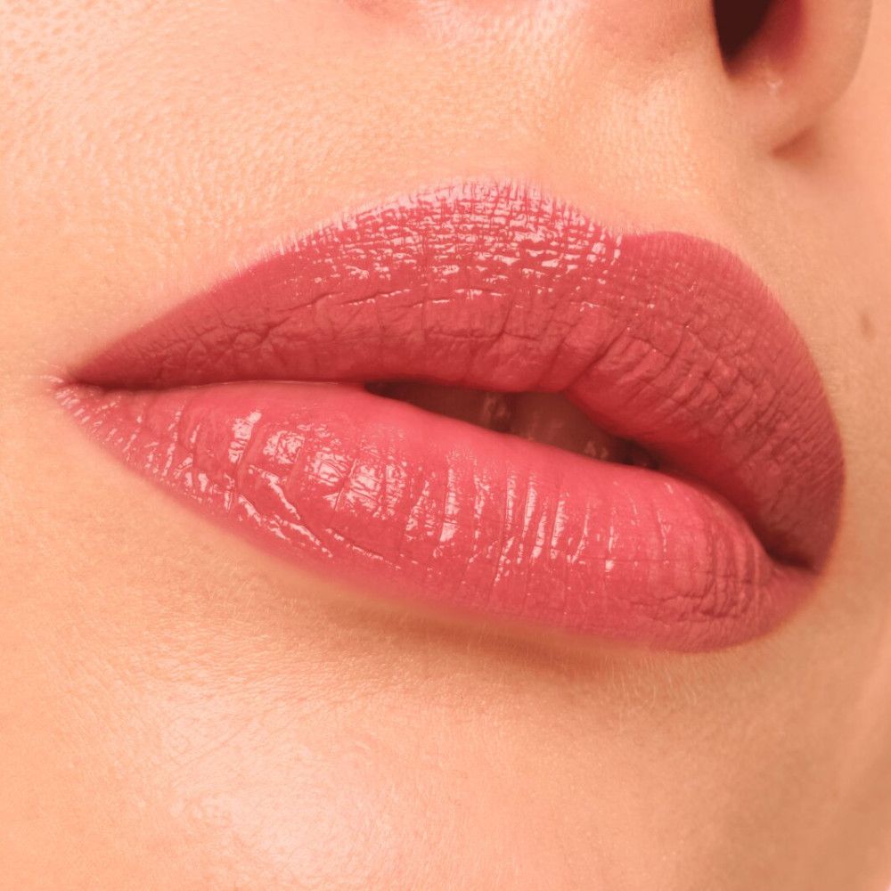 Nahaufnahme von Lippen mit rosafarbenem Gloss. Die Lippen sind leicht geöffnet und glänzend.