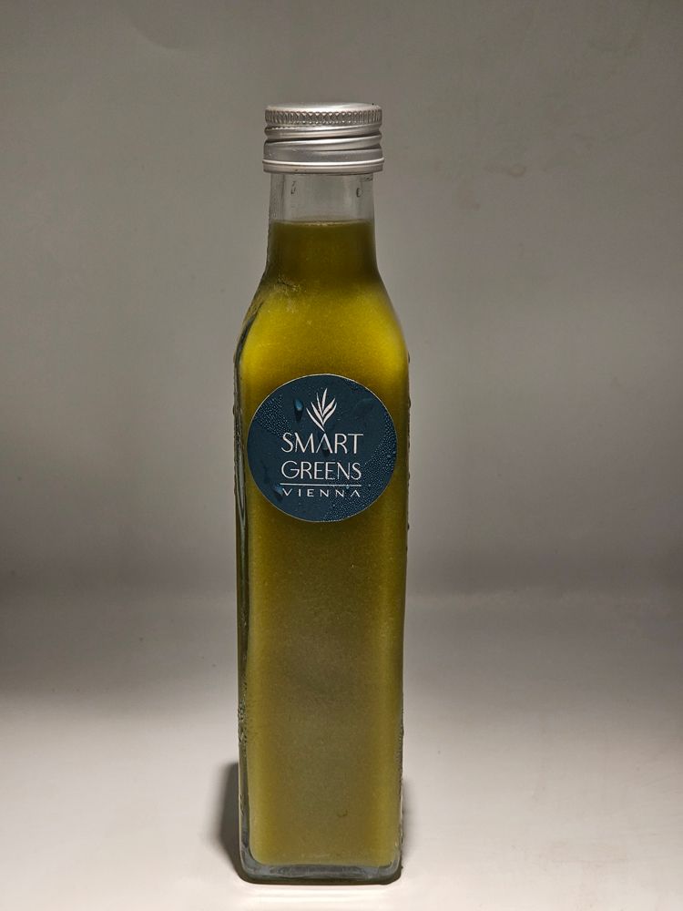Glasflasche mit grünem Inhalt und blauem Etikett. Aufschrift: SMART GREENS VIENNA.