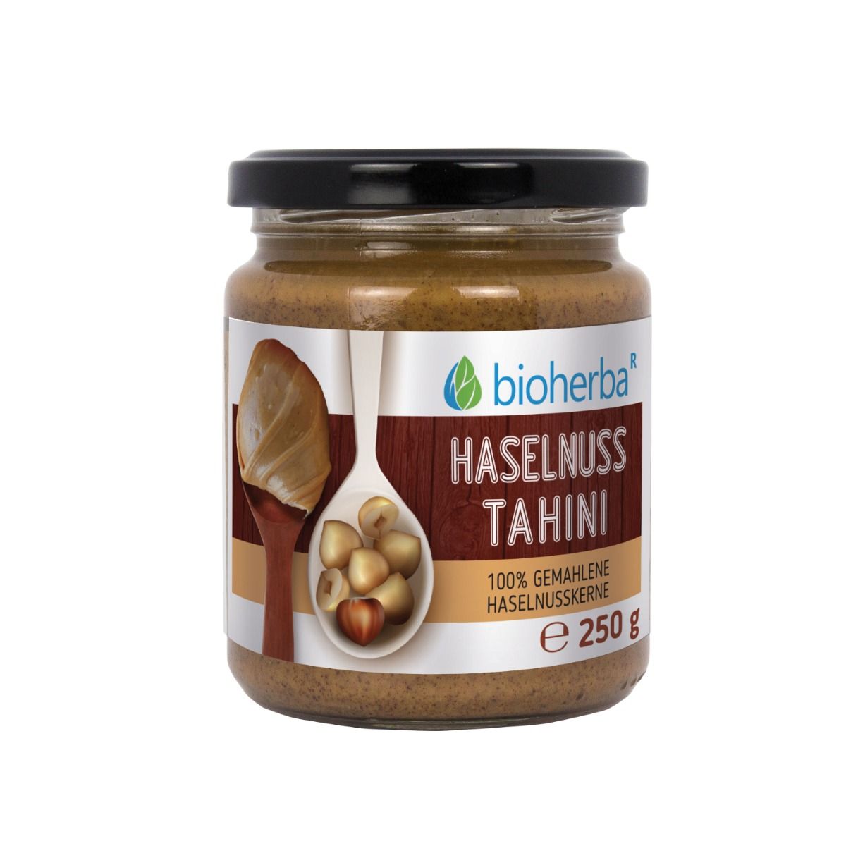 Glas mit Bioherba Haselnuss Tahini. Schwarzer Deckel, braunes Etikett mit Produktinformationen und Logo. E 250 g.