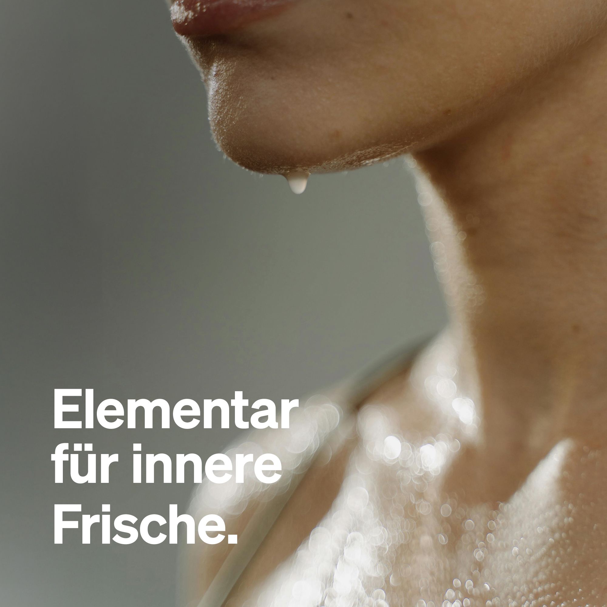 Nahaufnahme einer Person. Ein Tropfen Flüssigkeit fließt von der Unterlippe. Grauer Hintergrund.