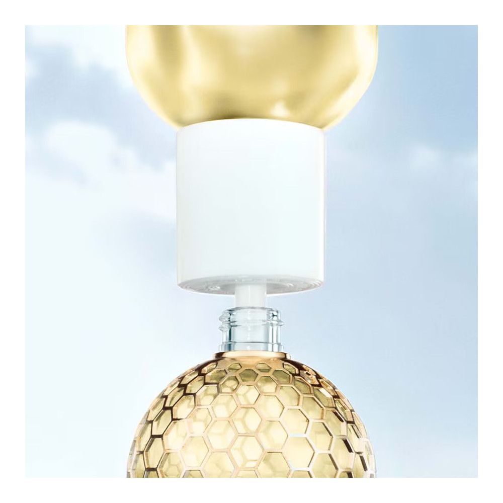 Goldfarbener Deckel und weißer Verschluss. Glasflasche mit goldfarbenem Wabenmuster. Klare Flüssigkeit sichtbar.