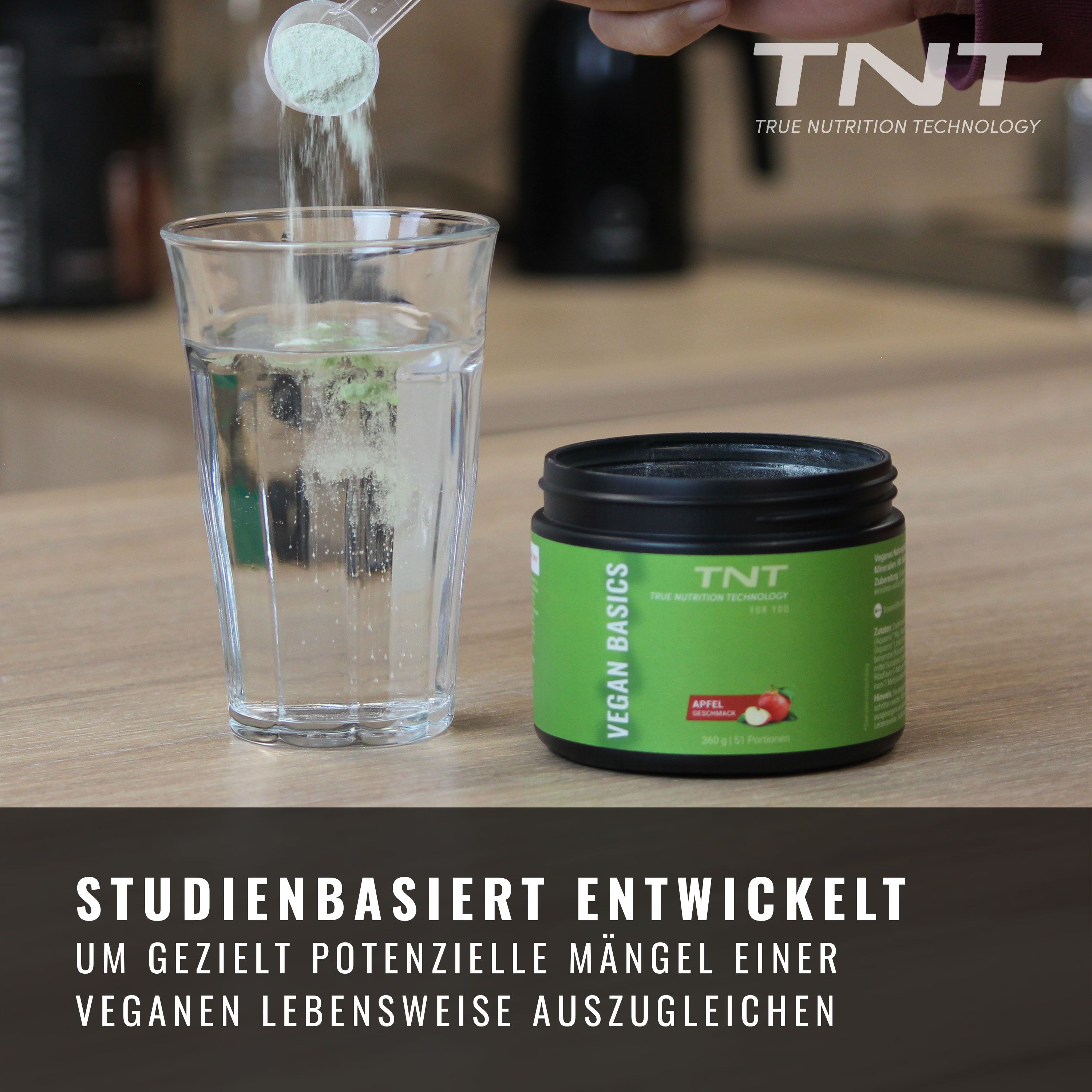 Pulver wird in Glas Wasser gegeben. Dose TNT Vegan Basics daneben. Text: Studienbasiert entwickelt.