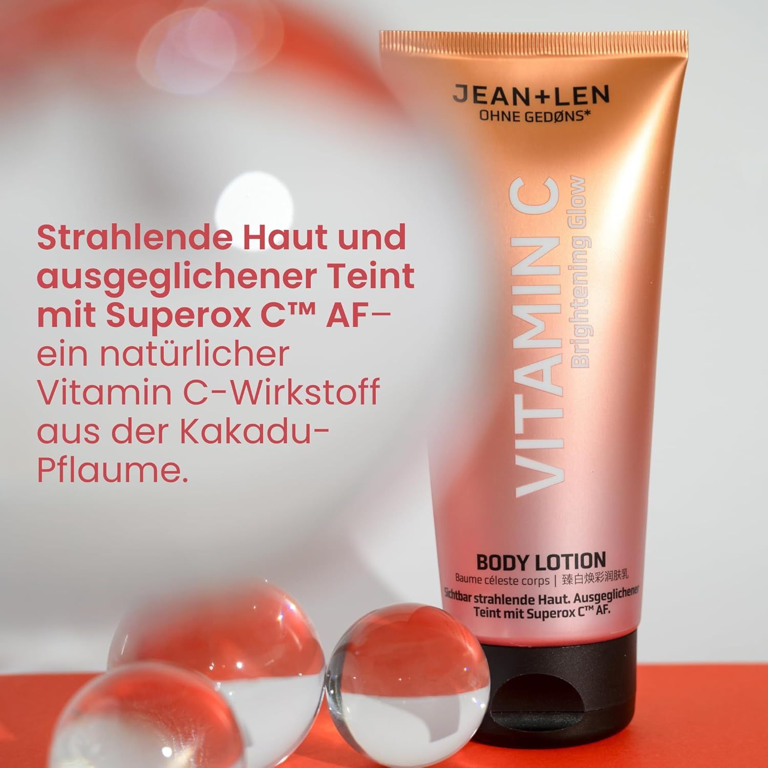 Tube Body Lotion Vitamin C, Marke Jean & Len. Rosa-goldener Farbverlauf. Text: Vitamin C, Body Lotion. Drei transparente Kugeln im Vordergrund.
