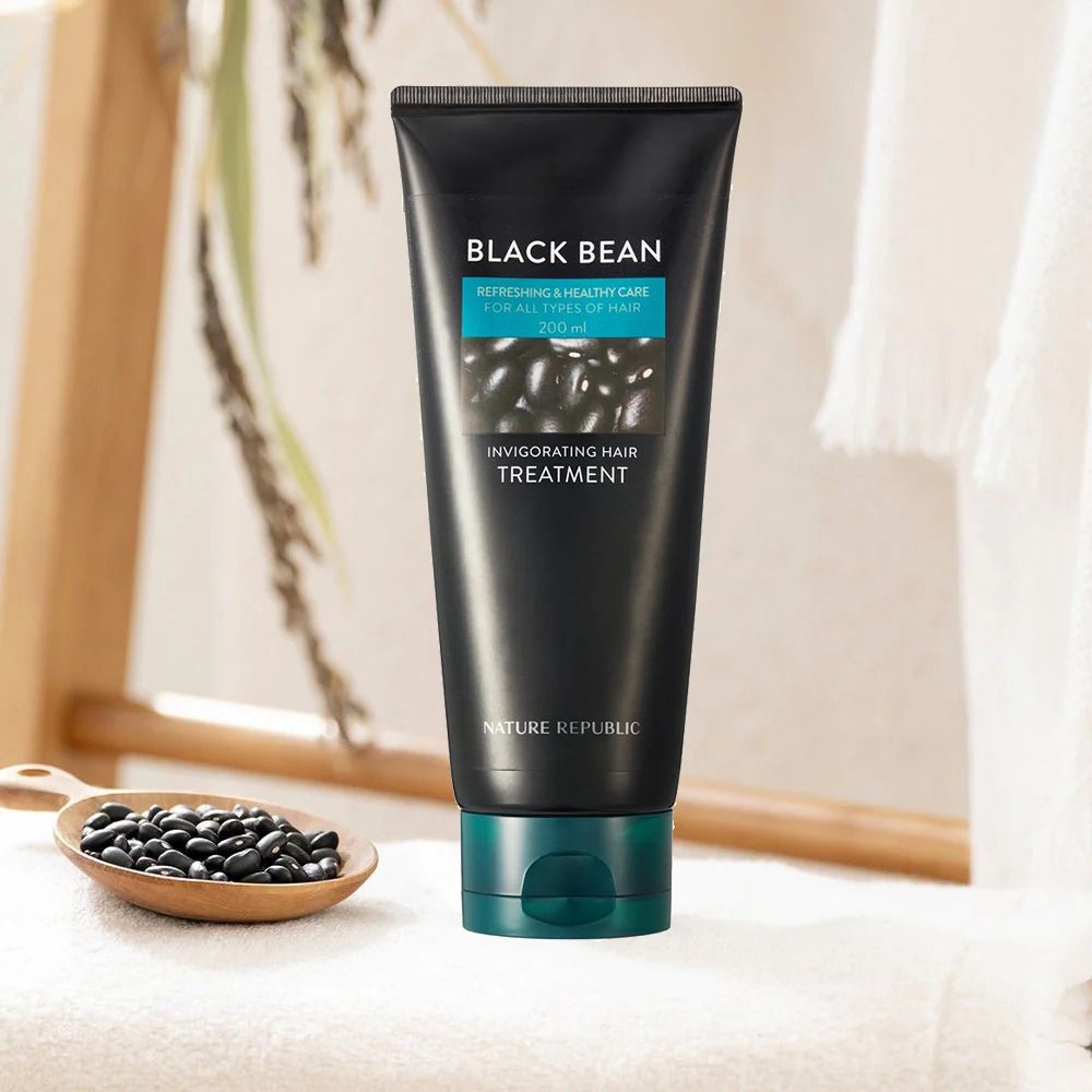 Schwarze Tube mit Produktnamen und Text. Türkisfarbener Streifen mit Produktinfo. Auf Handtuch und Löffel.