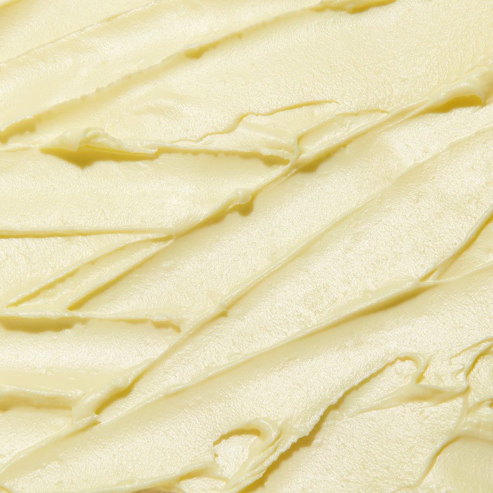 Nahaufnahme der cremigen Textur eines gelben Balsams mit Spuren.