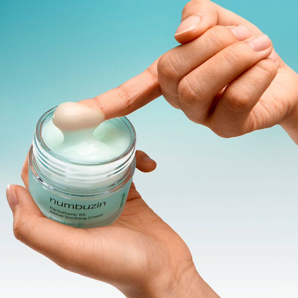 Eine Hand entnimmt mit dem Finger Numbuzin Pantothenic B5 Creme aus einem Glas.