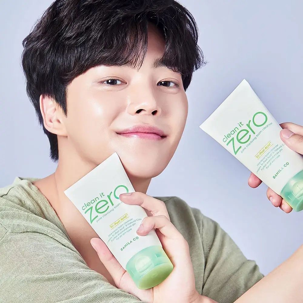 Ein Mann hält zwei Tuben "Clean it Zero" Reinigungsbalsam. Die Tuben sind weiß mit grünen Akzenten und Beschriftungen.