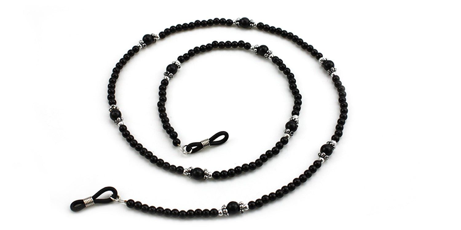 Brillenkette mit schwarzen Perlen und silberfarbenen Elementen. Die Kette ist in einer Spirale angeordnet.
