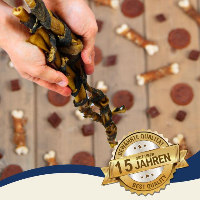 Hand hält Rinderkopfhautstange mit Pansen. Auf Holzuntergrund mit weiteren Snacks und Qualitätsauszeichnung.