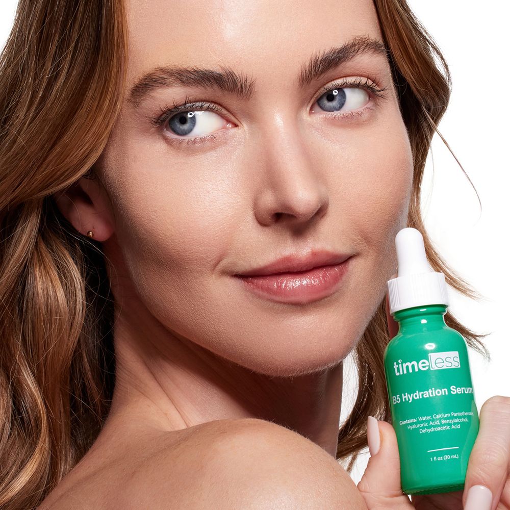 Frau hält grüne Flasche. Aufschrift: TIMELESS, B5 Hydration Serum. Frau mit blauen Augen.