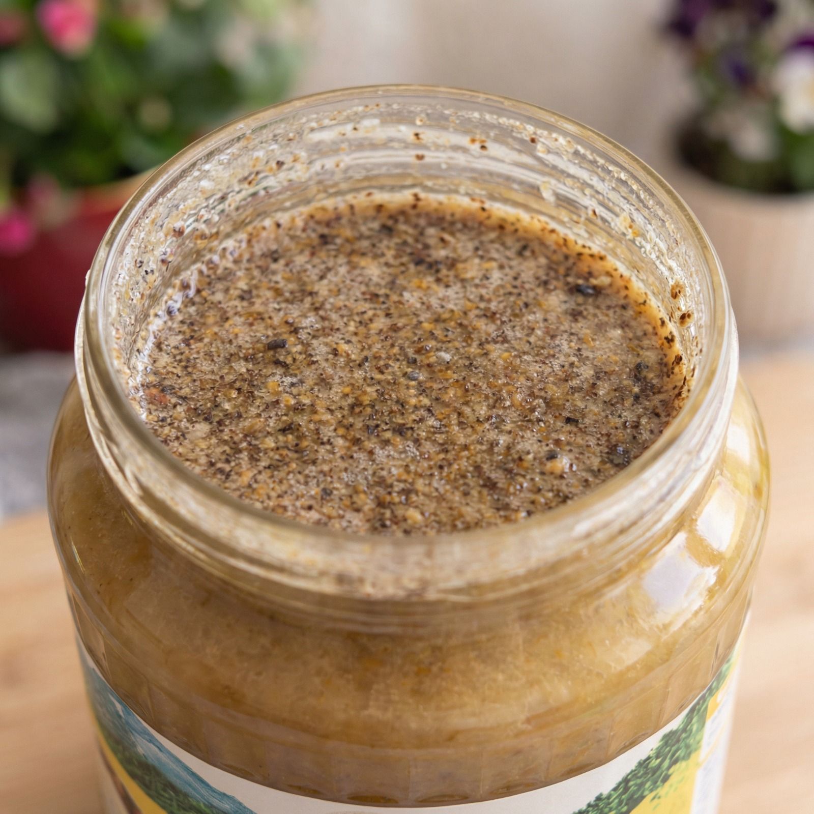 Nahaufnahme eines Glases mit Honig und Propolis. Die Oberfläche ist körnig und von dunkler Farbe.