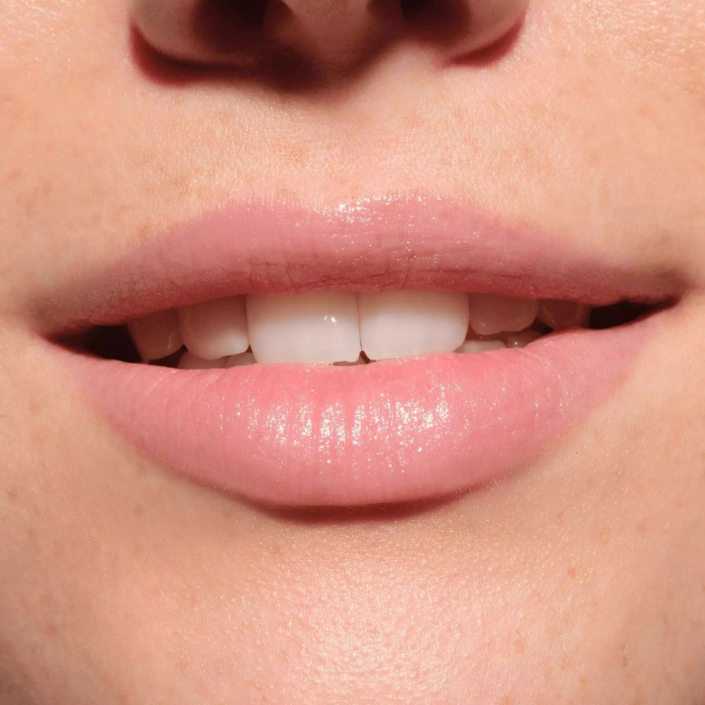 Nahaufnahme von geöffneten Lippen. Die Lippen sind mit einem rosafarbenen Balsam bedeckt.