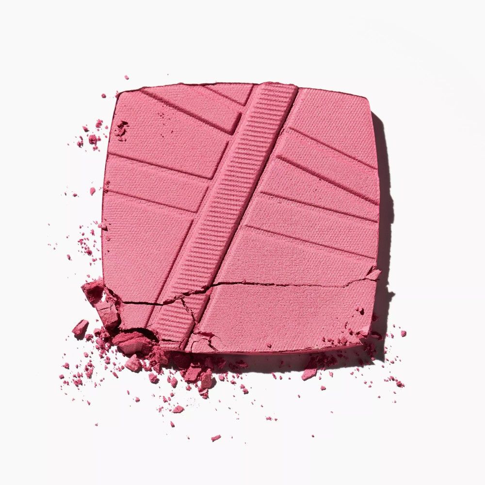 Zerbrochener rosa Catrice AirBlush Matte Puder. Quadratische Form mit diagonalen Linien. Puderfragmente auf weißem Hintergrund.