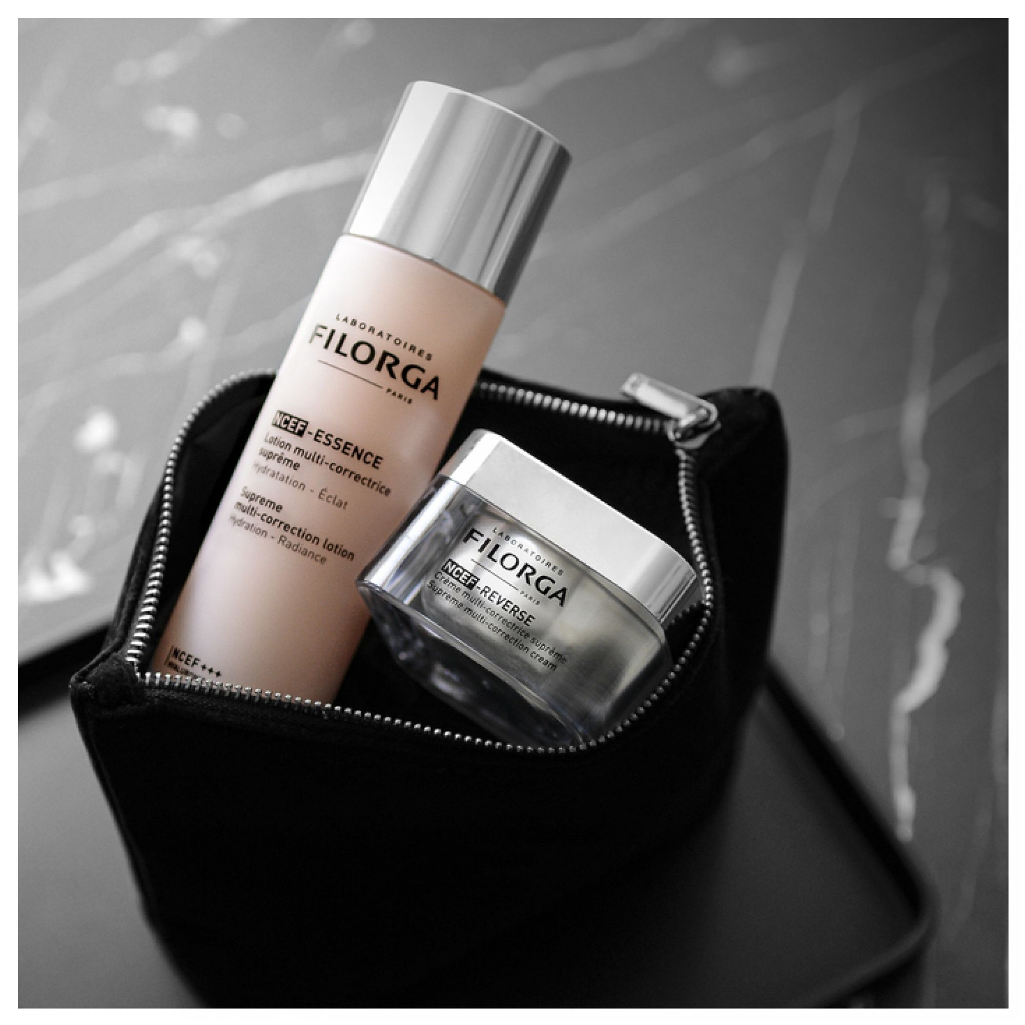 Filorga NCEF Essence Lotion und NCEF-Reverse Creme in einem schwarzen Kosmetikbeutel.