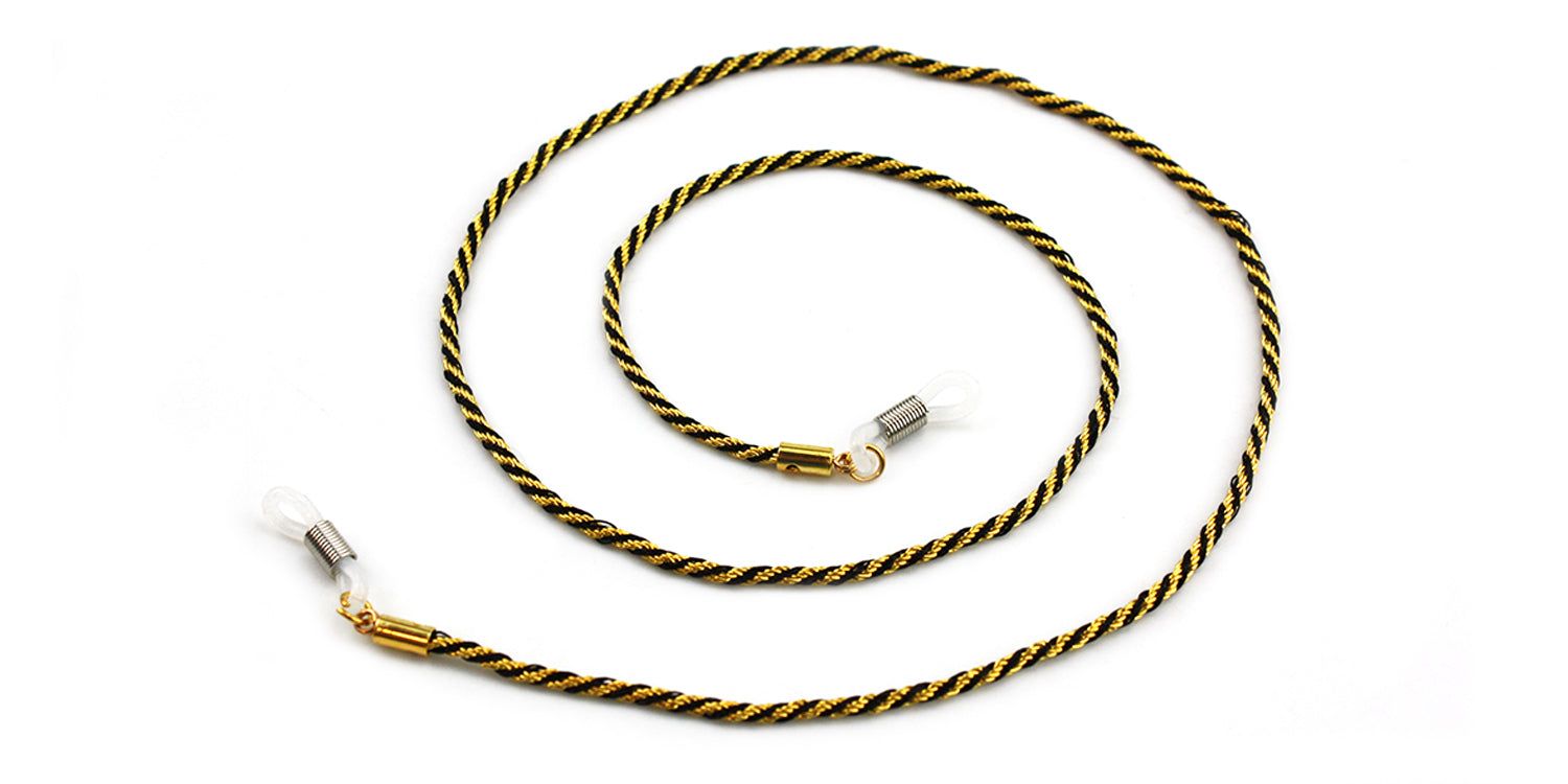 Brillenkette, goldfarbenes Seil, schwarze Akzente. Enden mit transparenten Schlaufen. Auf weißem Hintergrund.