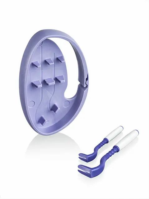 Lila Clipbox mit zwei Zeckenhaken. Der Clipbox hat eine ovale Form mit Griff und Halterungen für die Haken.
