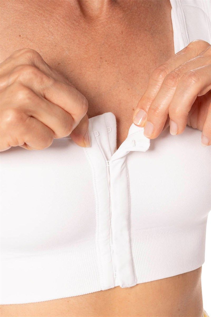 Weißes Oberteil mit Reißverschluss und Hakenverschluss. Nahaufnahme. Hände öffnen Verschluss.