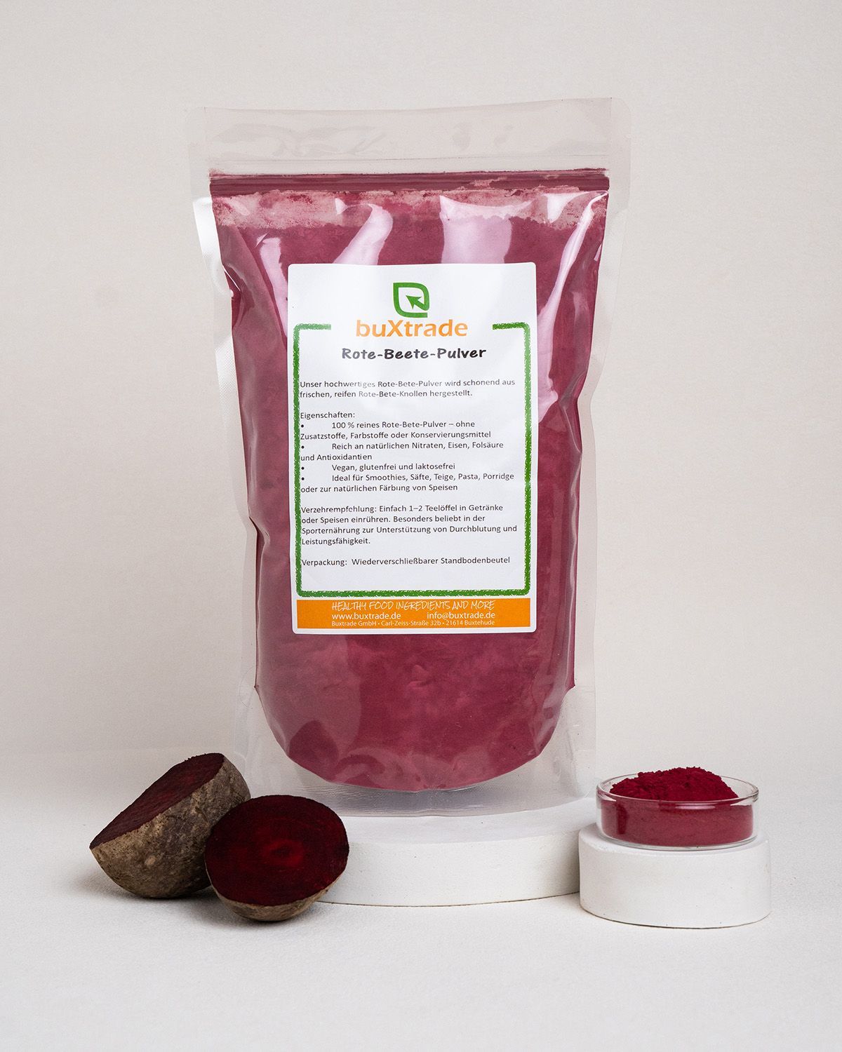 Rote Bete, halbiert und in Schale. Rotes Pulver in Schale auf Podest. Verpackung von buXtrade.