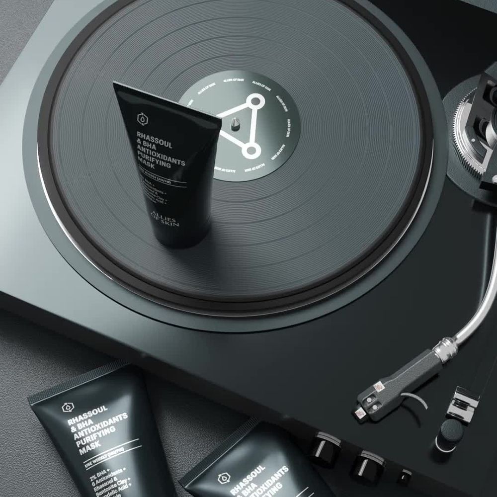 Drei schwarze Tuben auf einem Plattenspieler. Text: Rhassoul & BHA Antioxidants Purifying Mask. Schwarzer Hintergrund.