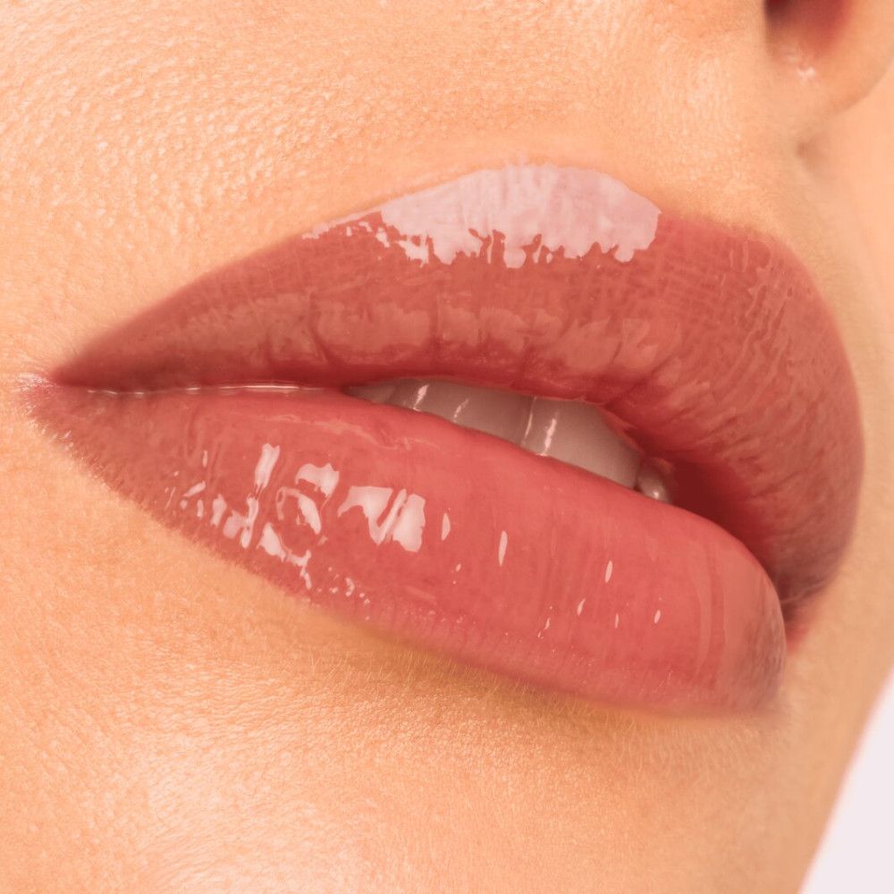 Nahaufnahme von Lippen mit aufgetragenem Lipgloss. Glänzende, rosafarbene Lippen.