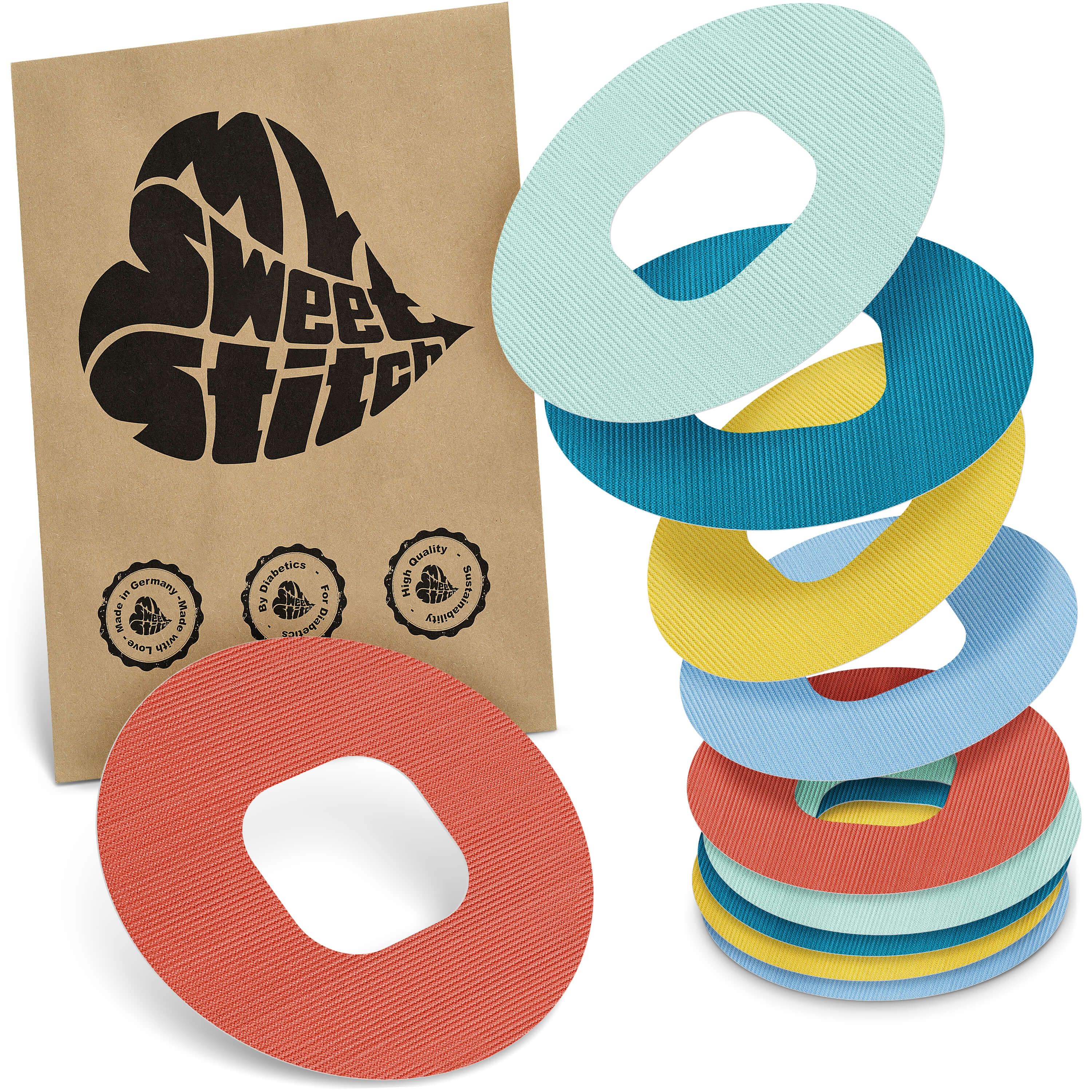 Mehrfarbige, ringförmige Pflaster mit Loch in der Mitte. Braune Verpackung mit Logo und Siegeln.