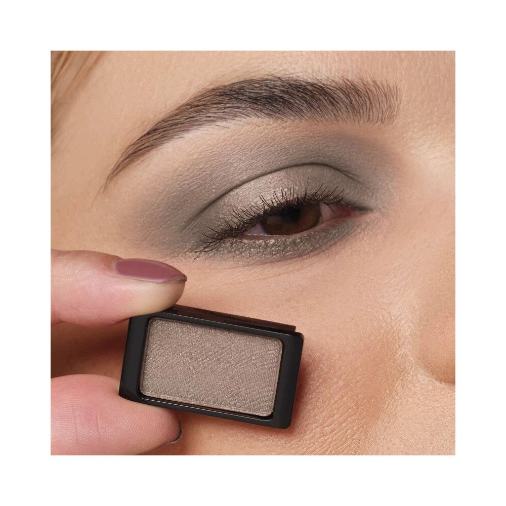 Artdeco Lidschatten Pearlfarben, grau. Rechteckige Form, in schwarzem Behälter. Gehalten vor einem Auge mit Lidschatten.
