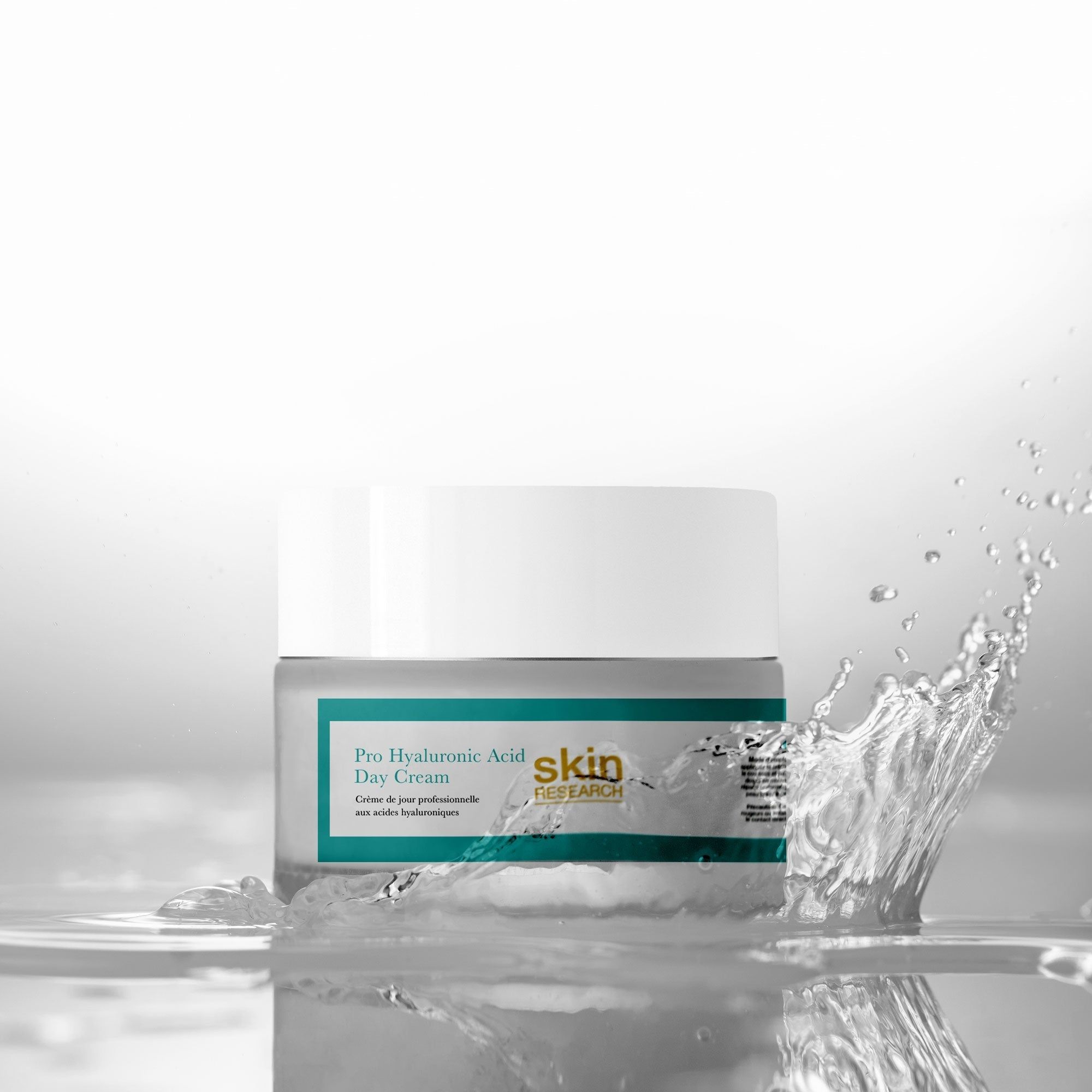 Creme-Glas mit Wasser. Aufschrift: Pro Hyaluronsäure Tagescreme. Marke: skin RESEARCH. Wasser spritzt.