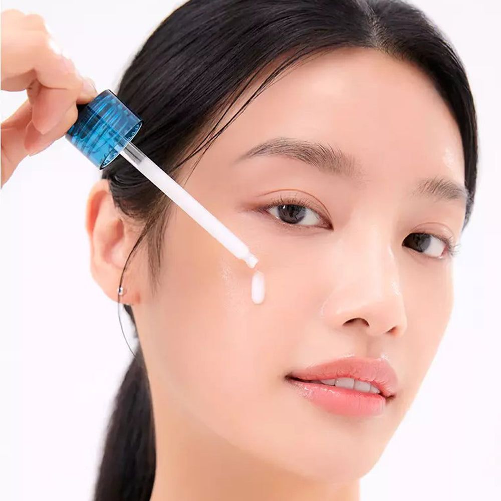 Eine Frau, die mit einer Pipette Serum auf ihr Gesicht aufträgt. Das Produkt ist nicht benannt.