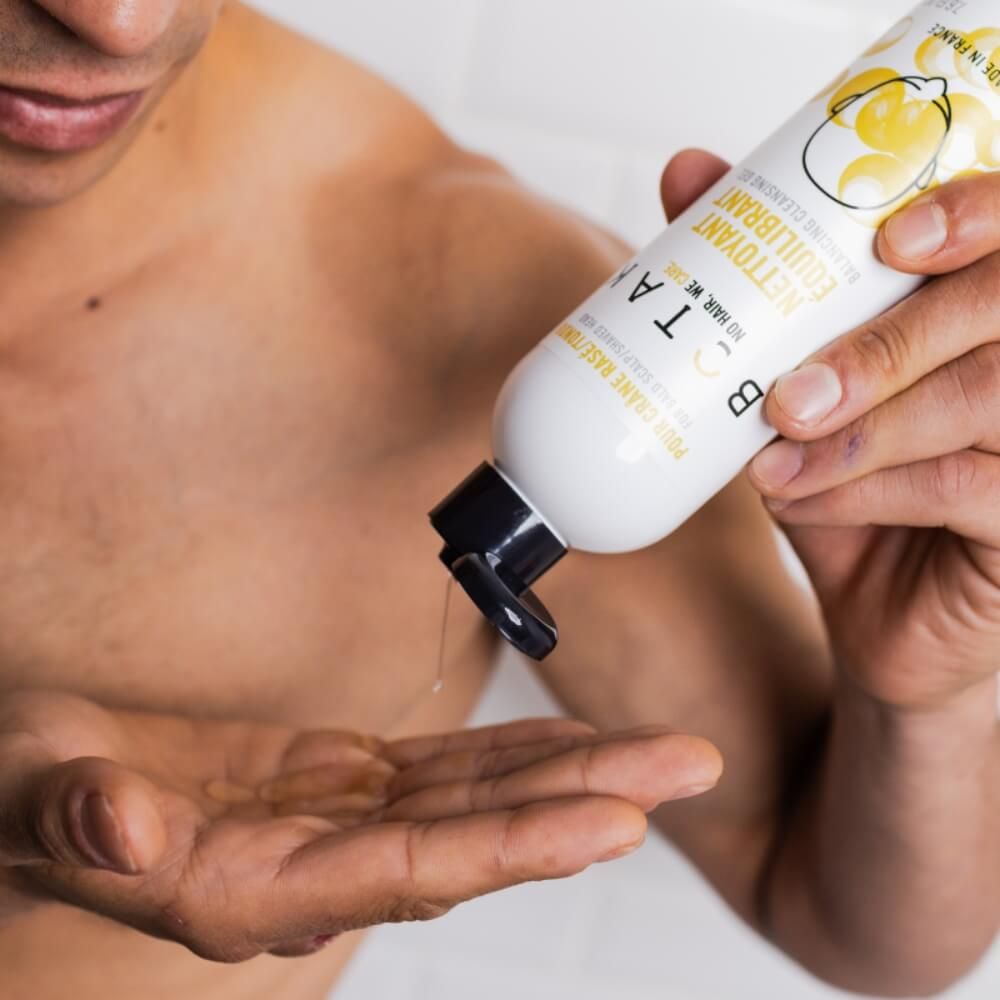 Mann gießt Flüssigkeit aus einer Flasche in seine Hand. Flasche mit Aufschrift BOTAK.