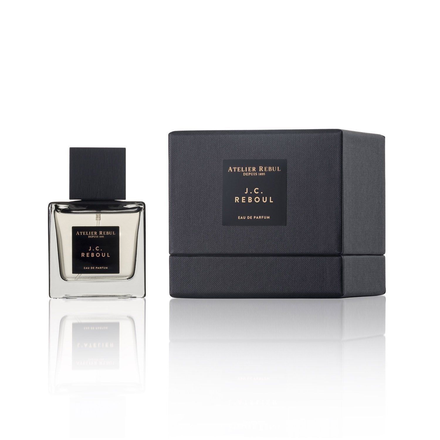 Quadratischer Glasflakon mit schwarzem Verschluss und schwarzer Verpackung. Aufschrift: Atelier Rebul J.C. Reboul Eau de Parfum.