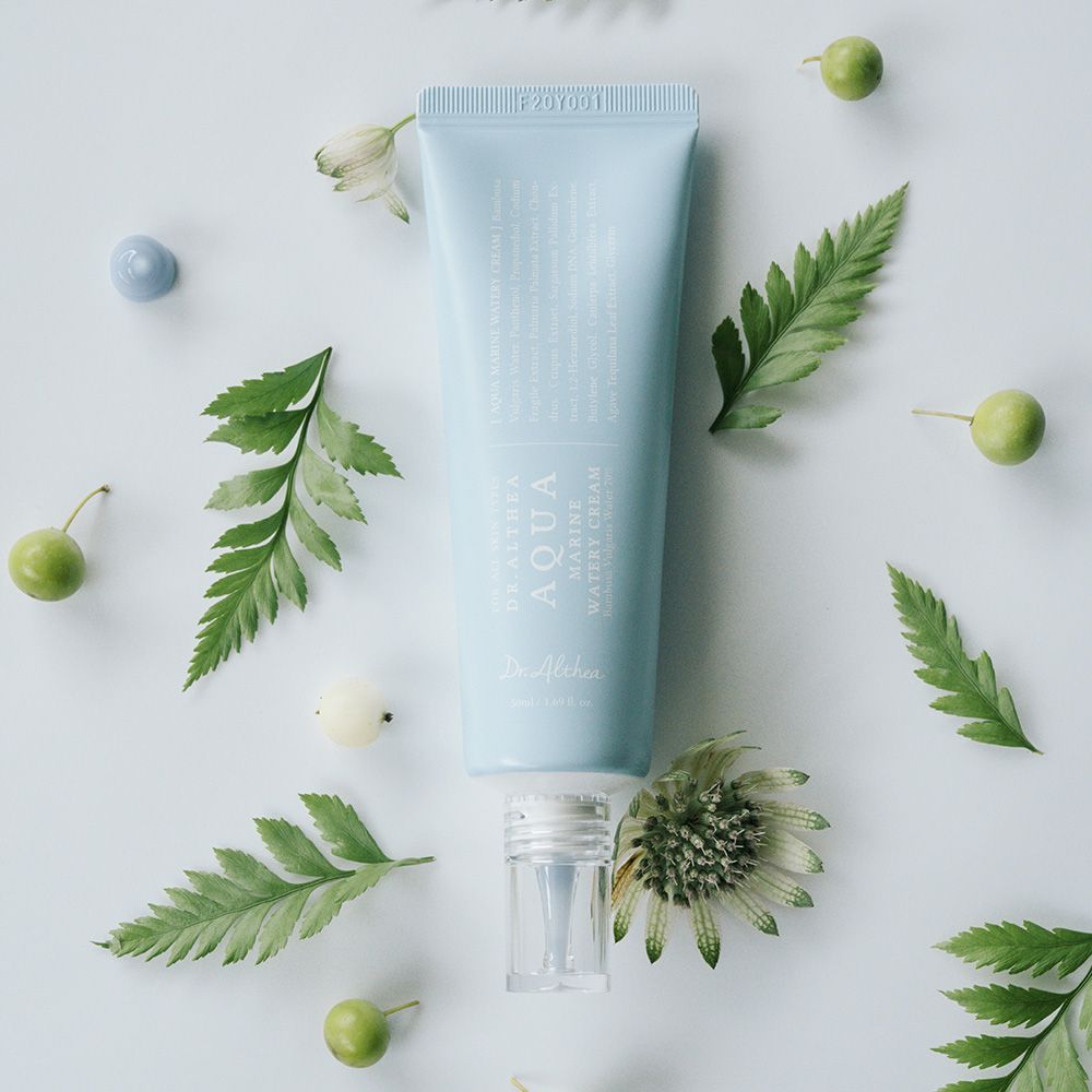 Hellblaue Tube mit Produkt, umgeben von Blättern und Früchten. Aufschrift: Aqua Marine Watery Cream.