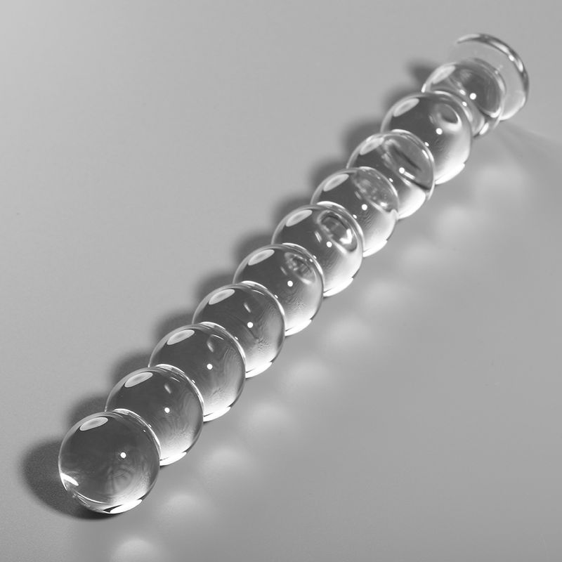Dildo aus Borosilikatglas. Klares Glas, kugelförmige Elemente. Auf hellem Hintergrund, diagonale Ausrichtung.