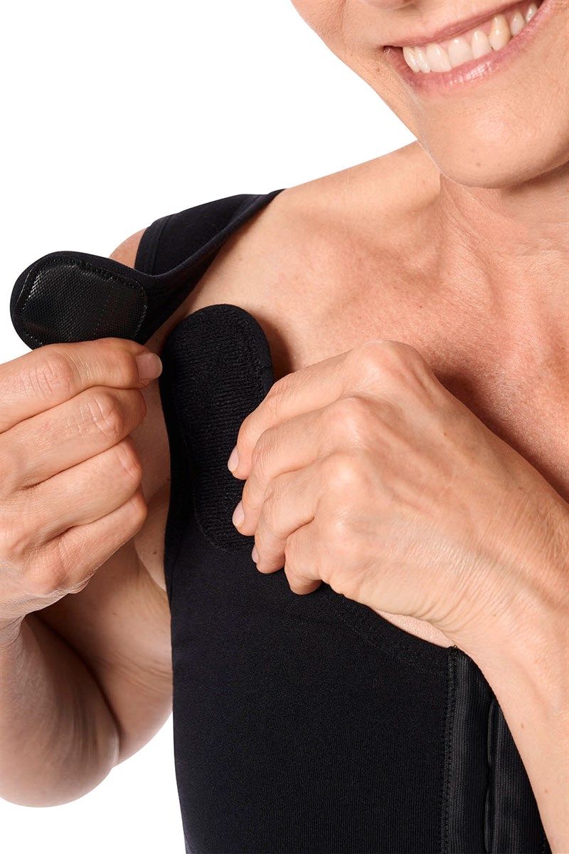 Schwarzer Post-OP BH. Schulterträger mit Klettverschluss. Frau hält Träger fest.