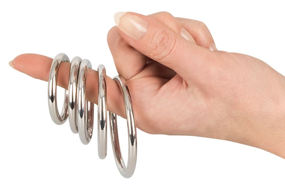 Hand mit fünf metallischen Penisringen auf einem Finger. Ringe aus glänzendem Metall.
