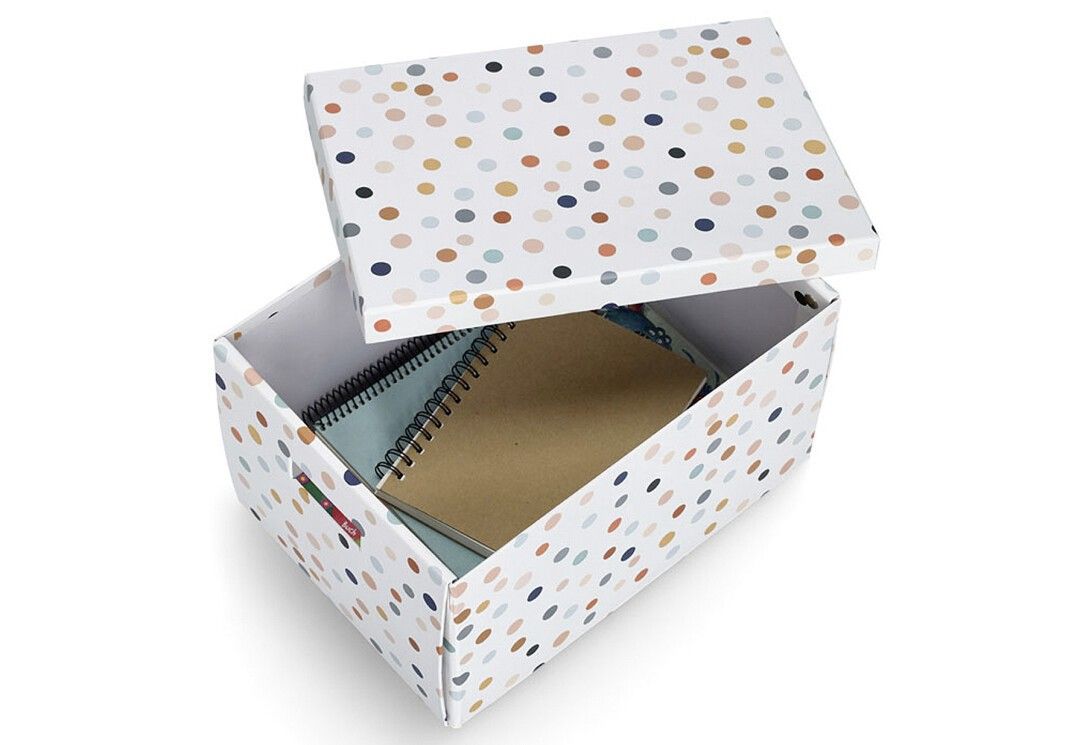 Aufbewahrungsbox mit Deckel, geöffnet. Weiß mit bunten Punkten. Innen: Notizbücher. Griffe an der Seite.