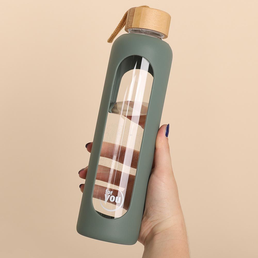 Hand hält grüne Glas-Trinkflasche mit Bambusdeckel und "for you" Logo.