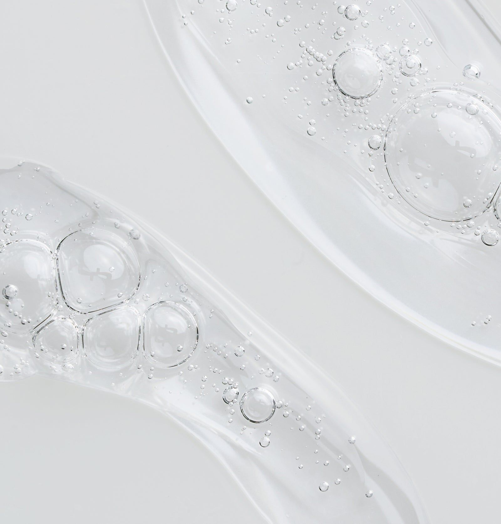 Nahaufnahme von transparentem Gel mit Blasen. Zwei Stränge, wellenförmig angeordnet. Helle, neutrale Umgebung.