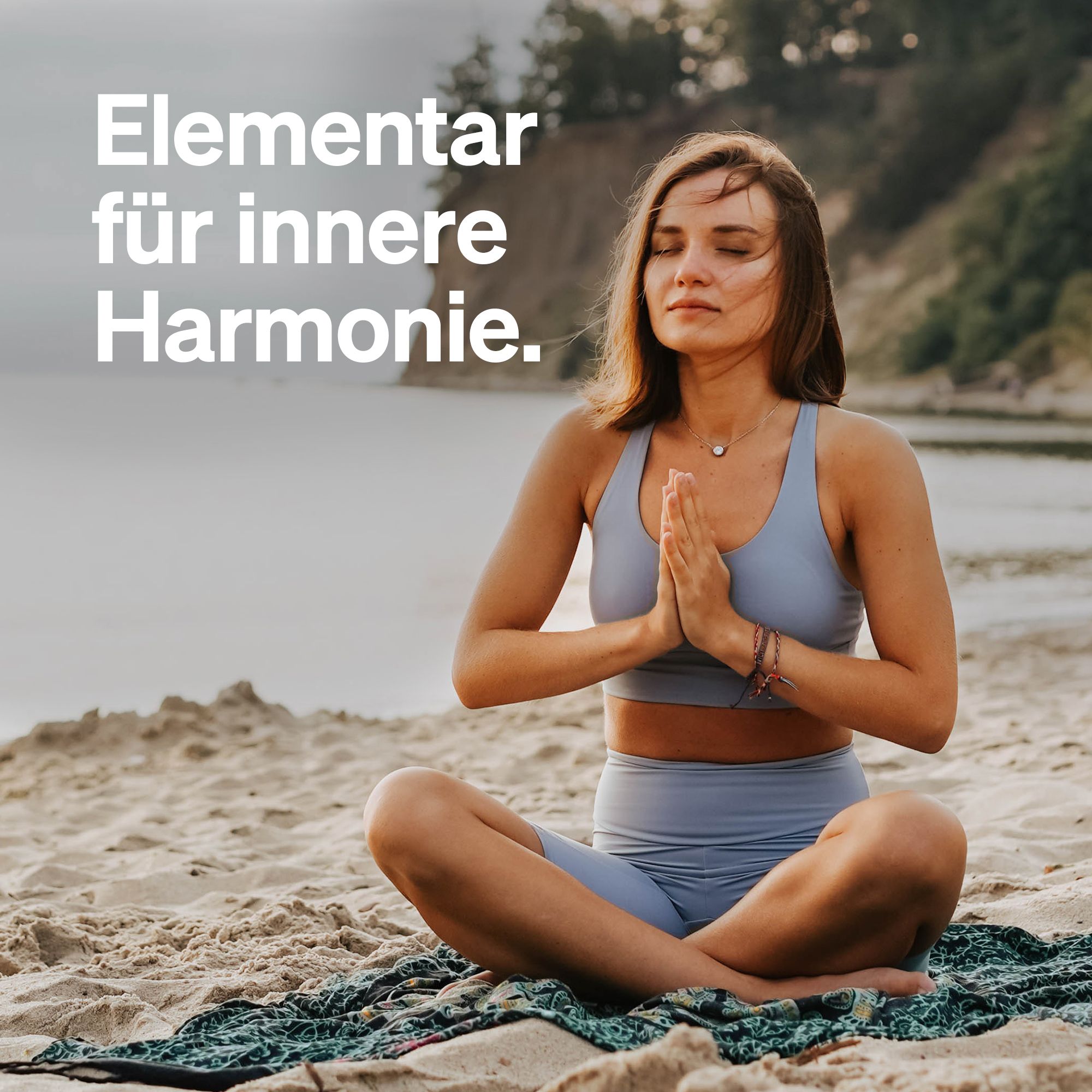 Frau sitzt am Strand in Yoga-Pose. Text: Elementar für innere Harmonie.