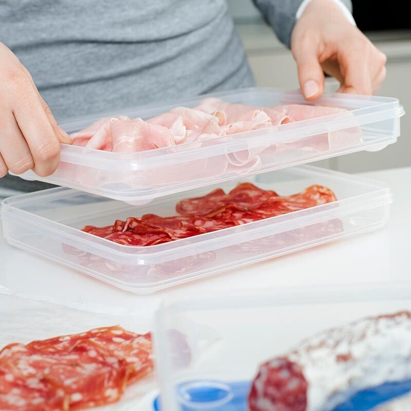 Zweiteilige, transparente Boxen mit Aufschnitt. Person hält die obere Box. Aufschnitt: Salami und Schinken.