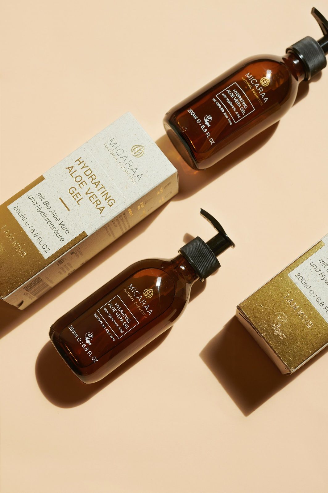 Mehrere braune Glasflaschen mit schwarzem Pumpverschluss und Kartons. Beschriftung: MICARAA, Hydrating Aloe Vera Gel, 200ml/6.8 FL OZ, vegan.