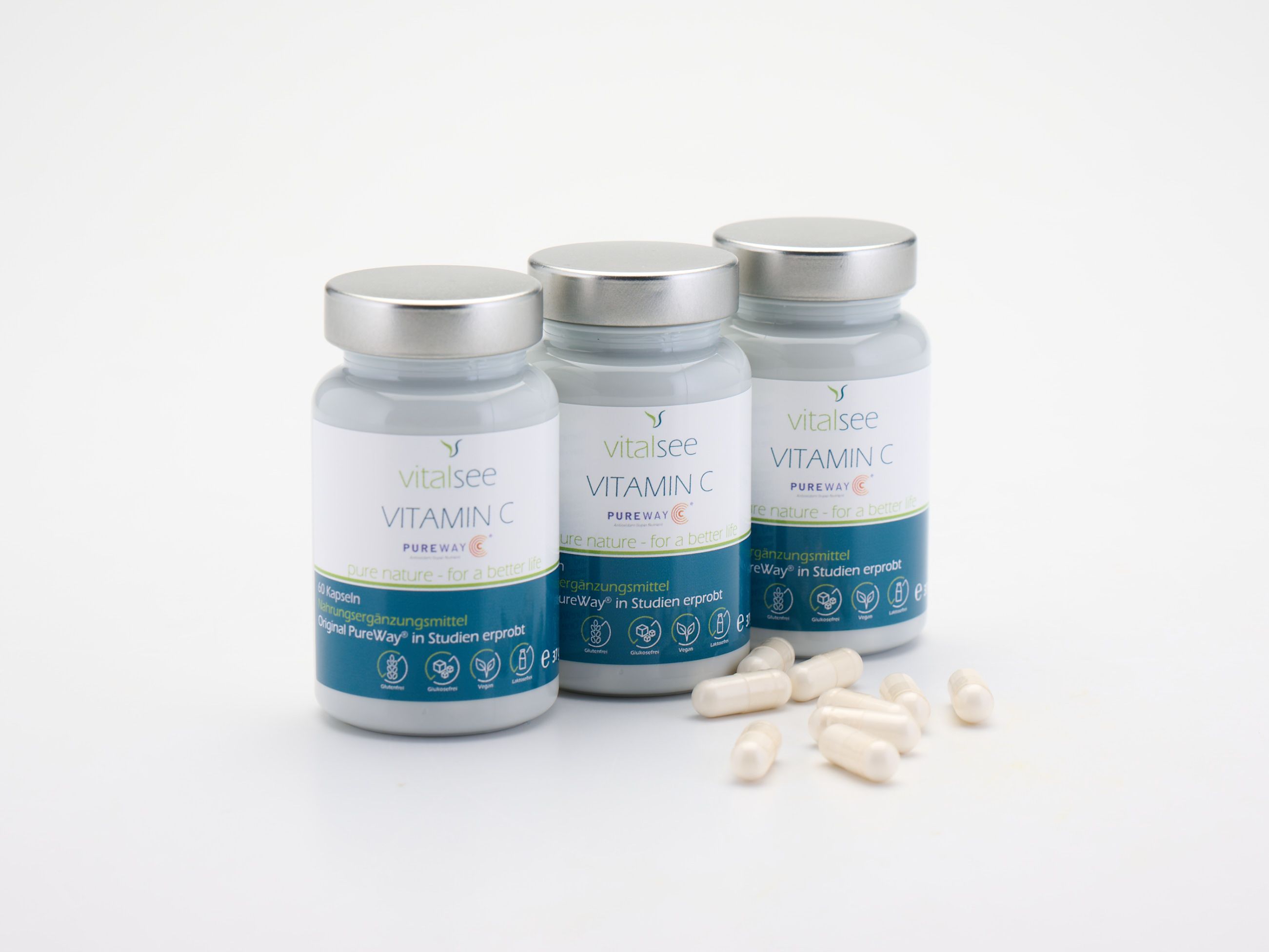 Drei Flaschen Vitalsee Vitamin C und Kapseln. Graue Flaschen mit silbernen Deckeln.
