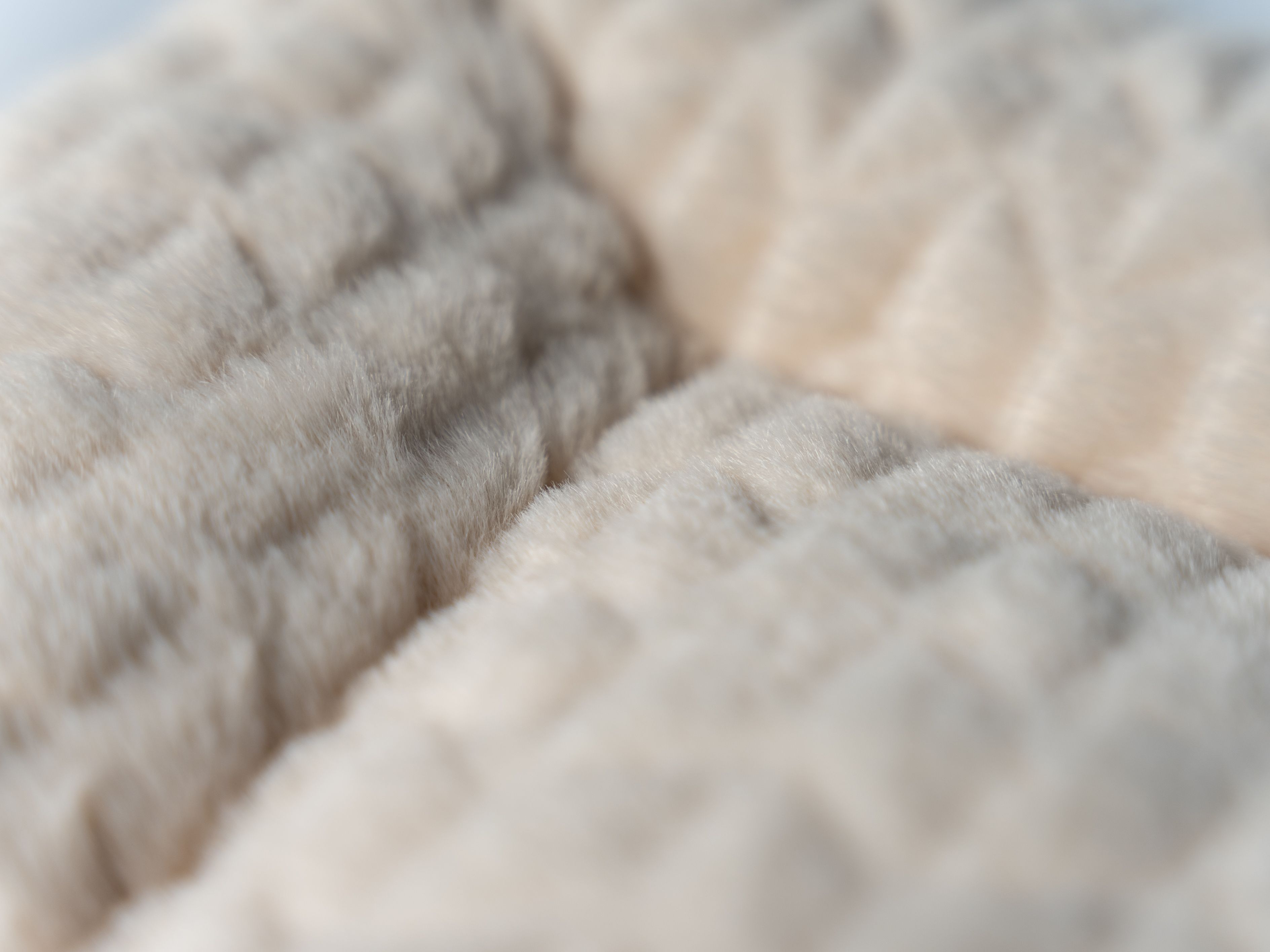 Nahaufnahme der cremefarbenen, gefütterten Liegedecke. Die Oberfläche ist weich und strukturiert.