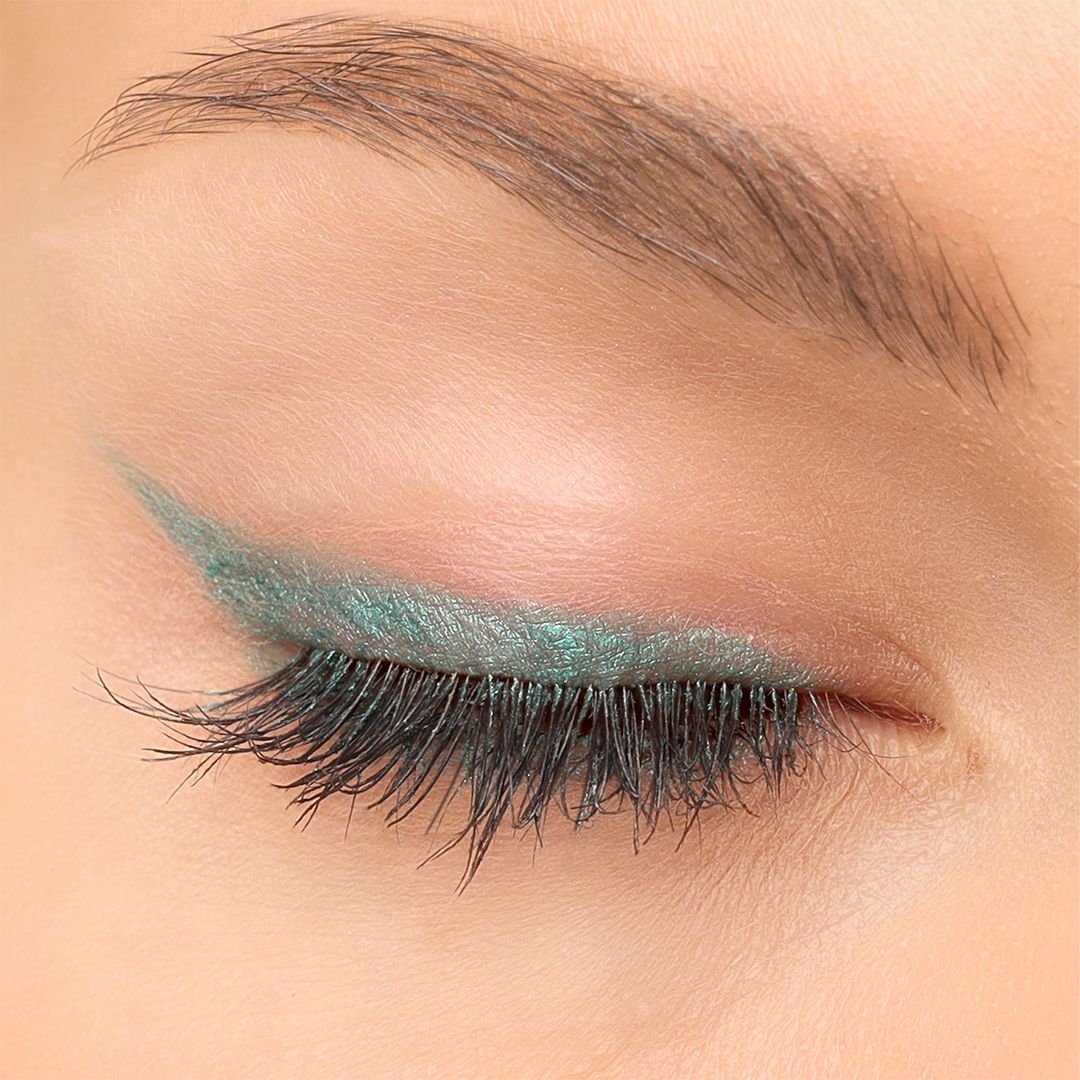 Geschlossenes Auge mit grünem Kajal-Eyeliner. Lange Wimpern. Hautton. Der Eyeliner ist am oberen Lid aufgetragen.