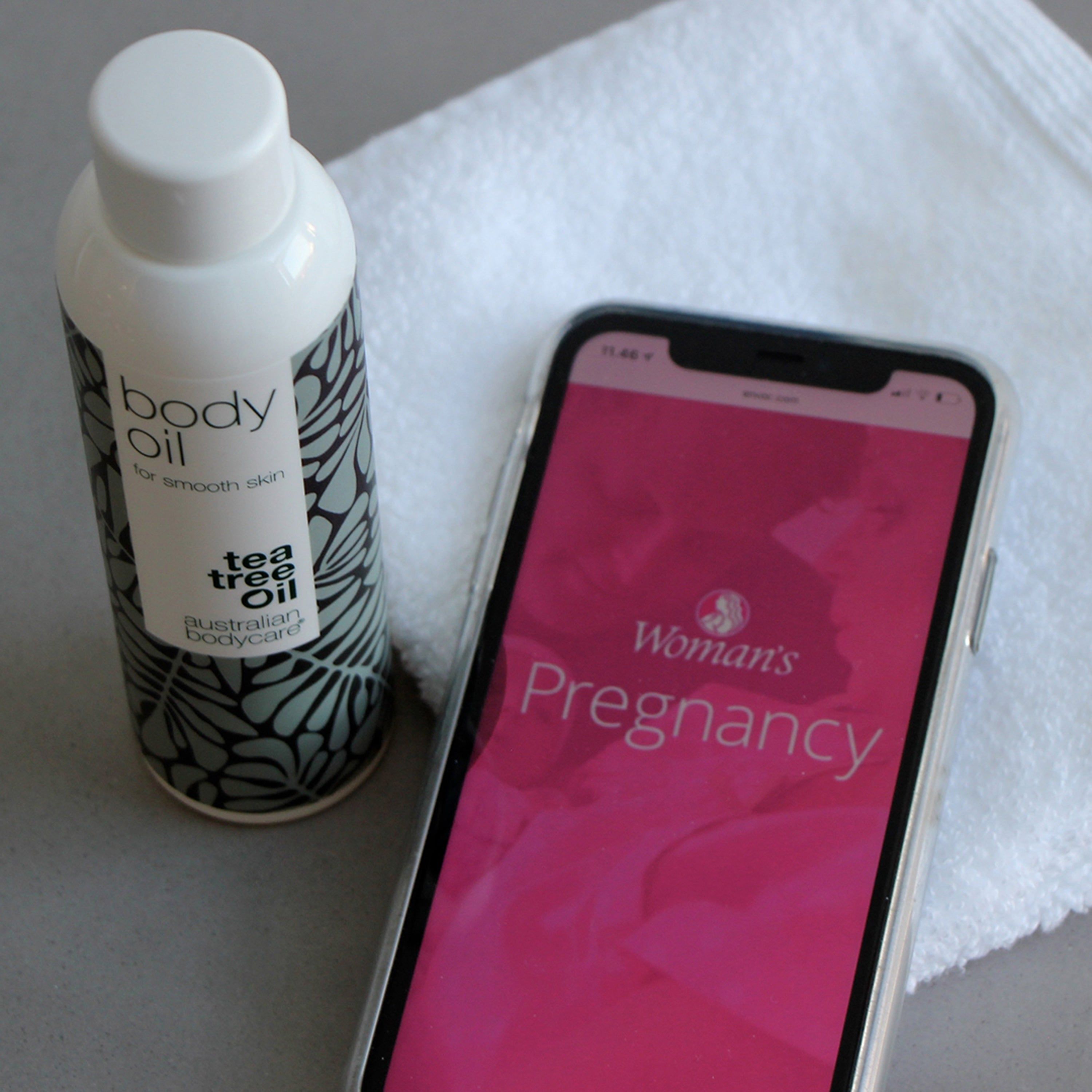 Flasche mit Etikett, daneben ein Smartphone mit App-Anzeige und ein weißes Handtuch.