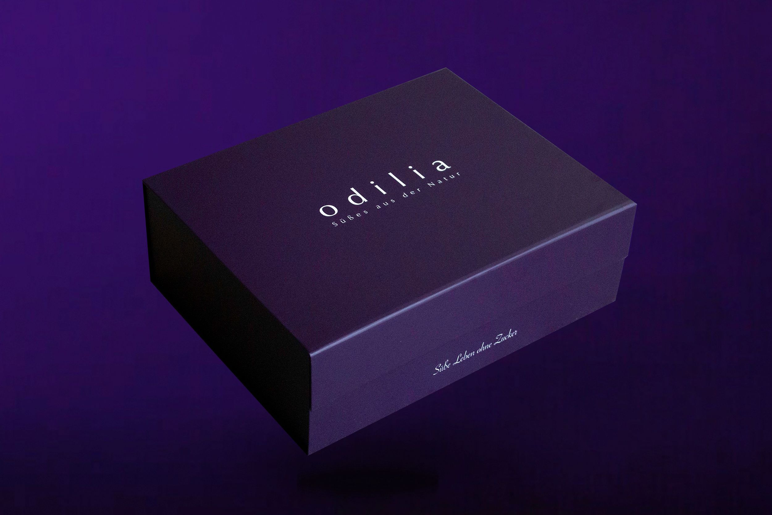 Geschlossene lila Geschenkbox mit Odilia Logo.