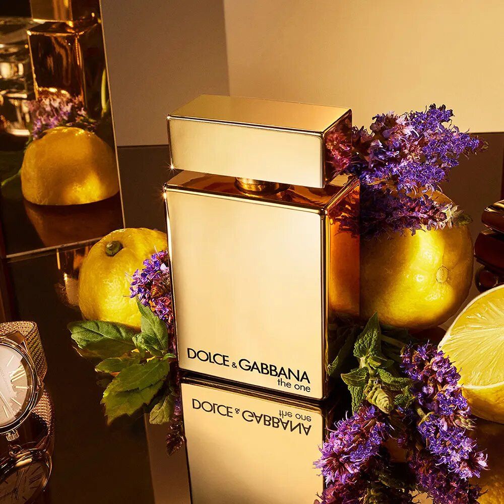 Goldfarbener Flakon, umgeben von Zitronen, Lavendel und einer Uhr. Aufschrift: Dolce & Gabbana the one.
