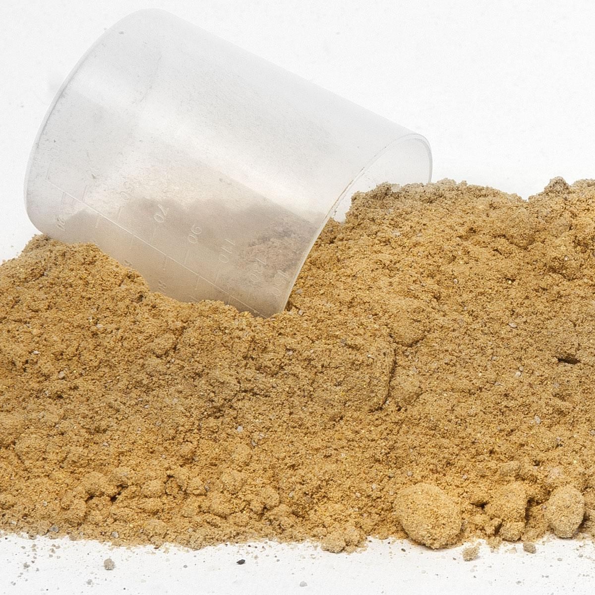 Haufen braunes Pulver mit Messbecher. Der Messbecher ist teilweise im Pulver vergraben.
