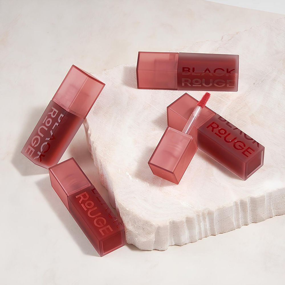 Mehrere Lipgloss-Flakons. Schwarze Schrift: BLACK ROUGE. Rosa Deckel und Flakons. Roter Inhalt. Auf weißem Untergrund.
