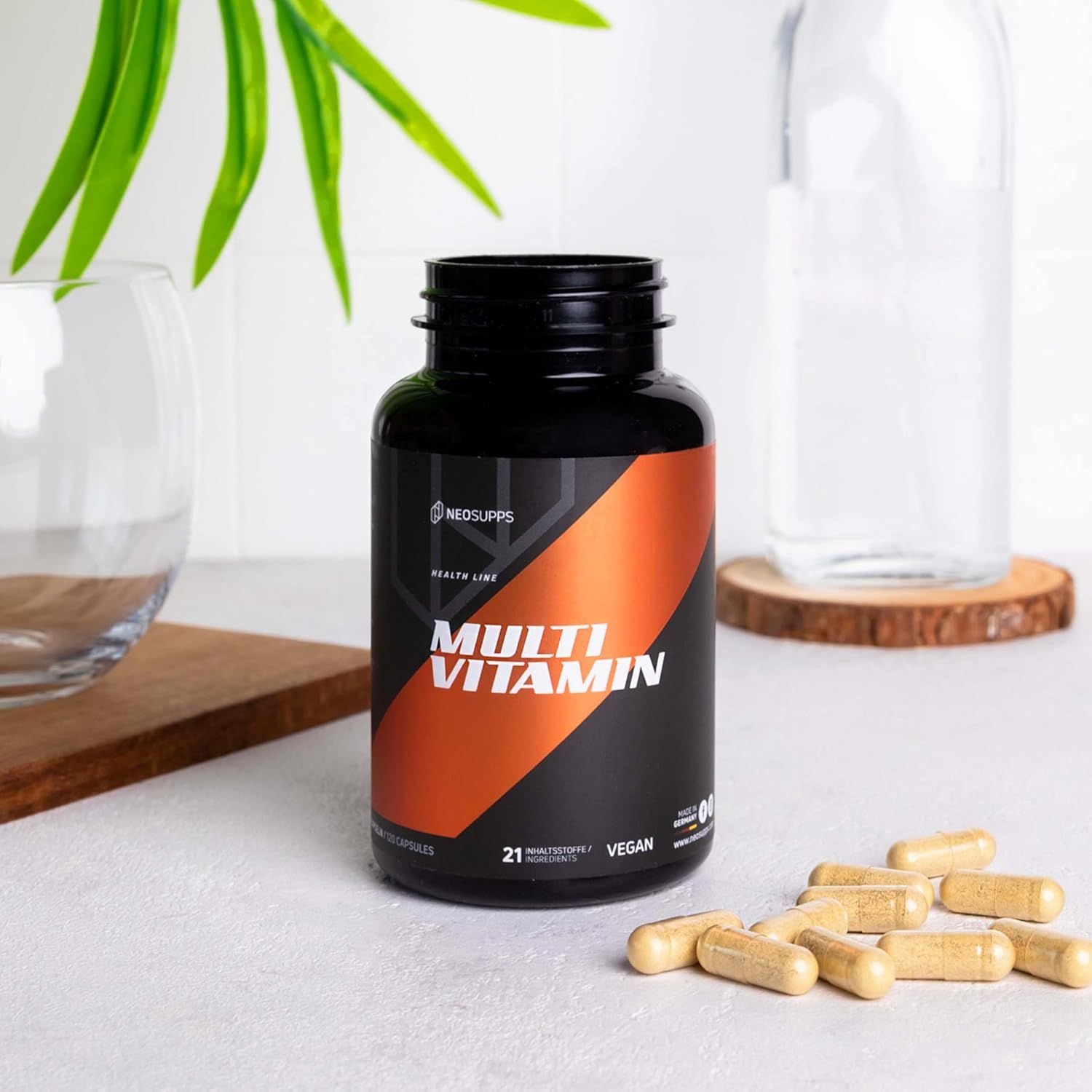 Schwarze Flasche "Multi Vitamin" mit Kapseln daneben. 21 Inhaltsstoffe, vegan. Auf hellem Untergrund.